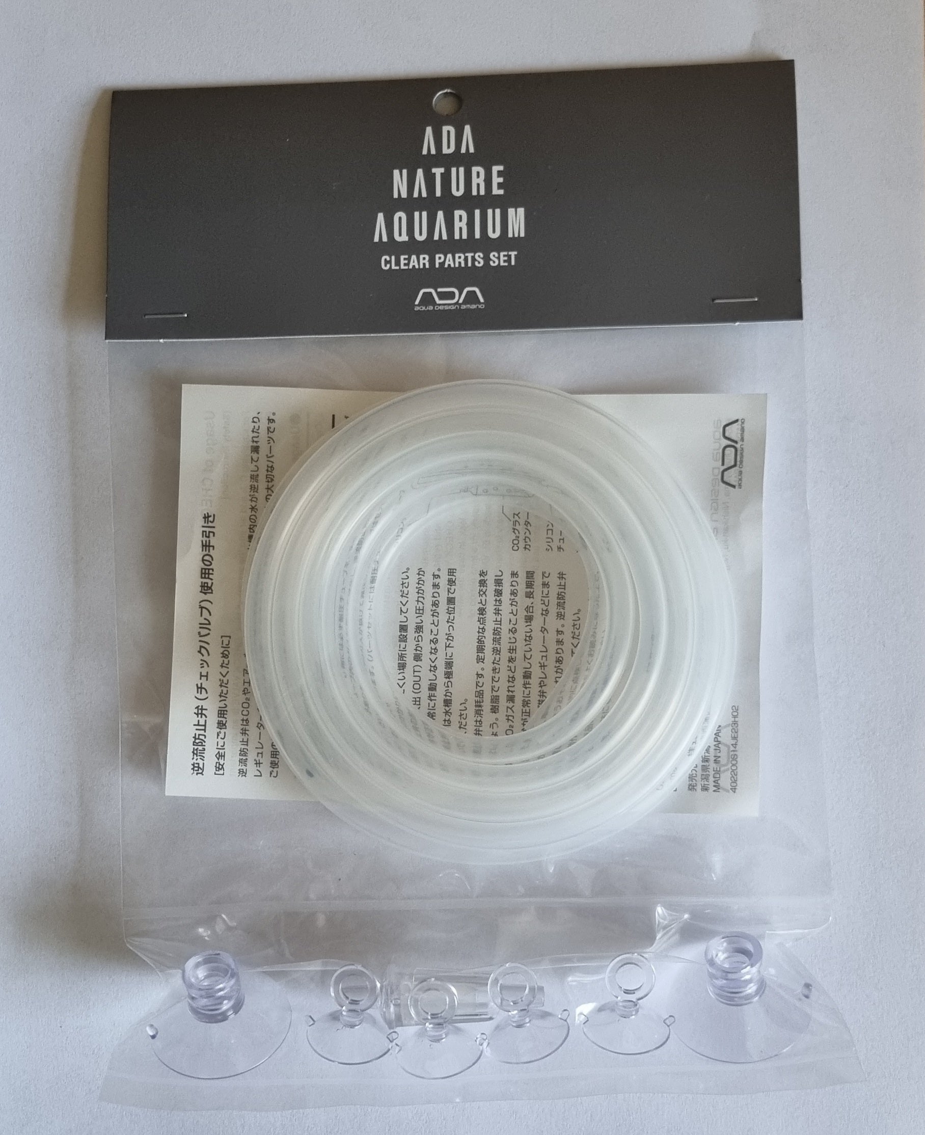 Das Bild zeigt eine Verpackung mit dem Schriftzug "ADA Nature Aquarium Clear Parts Set". Darin befindet sich ein Satz transparenter Schlauchstücke und Saugnäpfe.