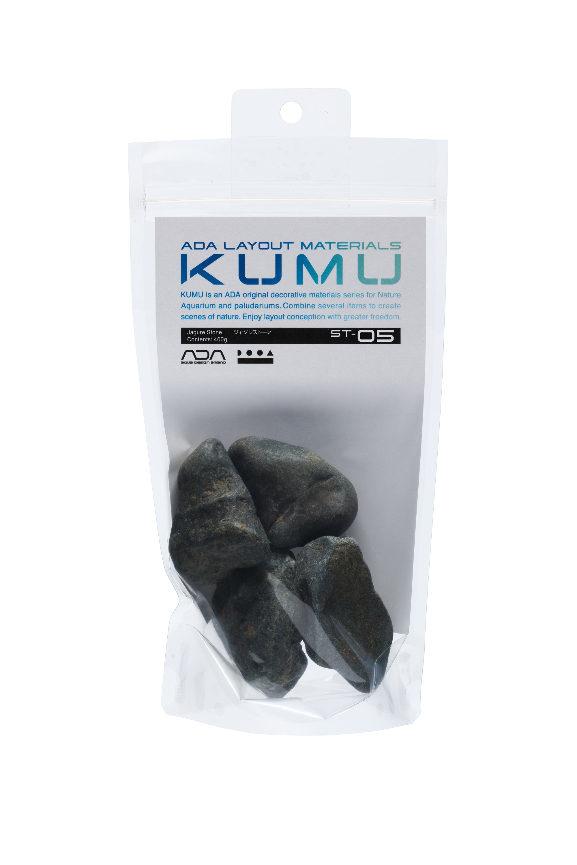 Beschreibung des Bildes: ADA Kumu Jagure Stone
Das Bild zeigt eine transparente Verpackung mit einem weißen Etikett. Darin befinden sich mehrere dunkle, glattgeschliffene Steine unterschiedlicher Größe. Die Steine haben eine unregelmäßige, natürliche Form und eine leicht glänzende Oberfläche.