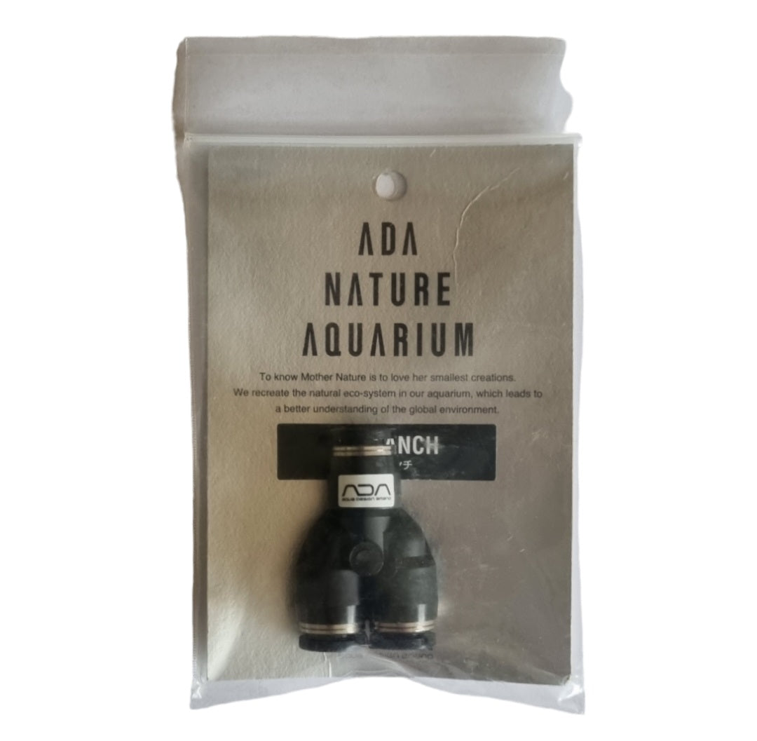 In der Verpackung befindet sich ein schwarzes Kunststoffteil mit einer Y-förmigen oder T-förmigen Struktur.