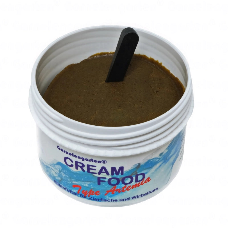 Weiße Plastikdose mit schwarzem Messlöffel. Darin befindet sich braunes Cremfutter. Beschriftung: Garnelengarten® Cream Food Type Artemia. Alleinfutter für Zierfische und Wirbellose.
